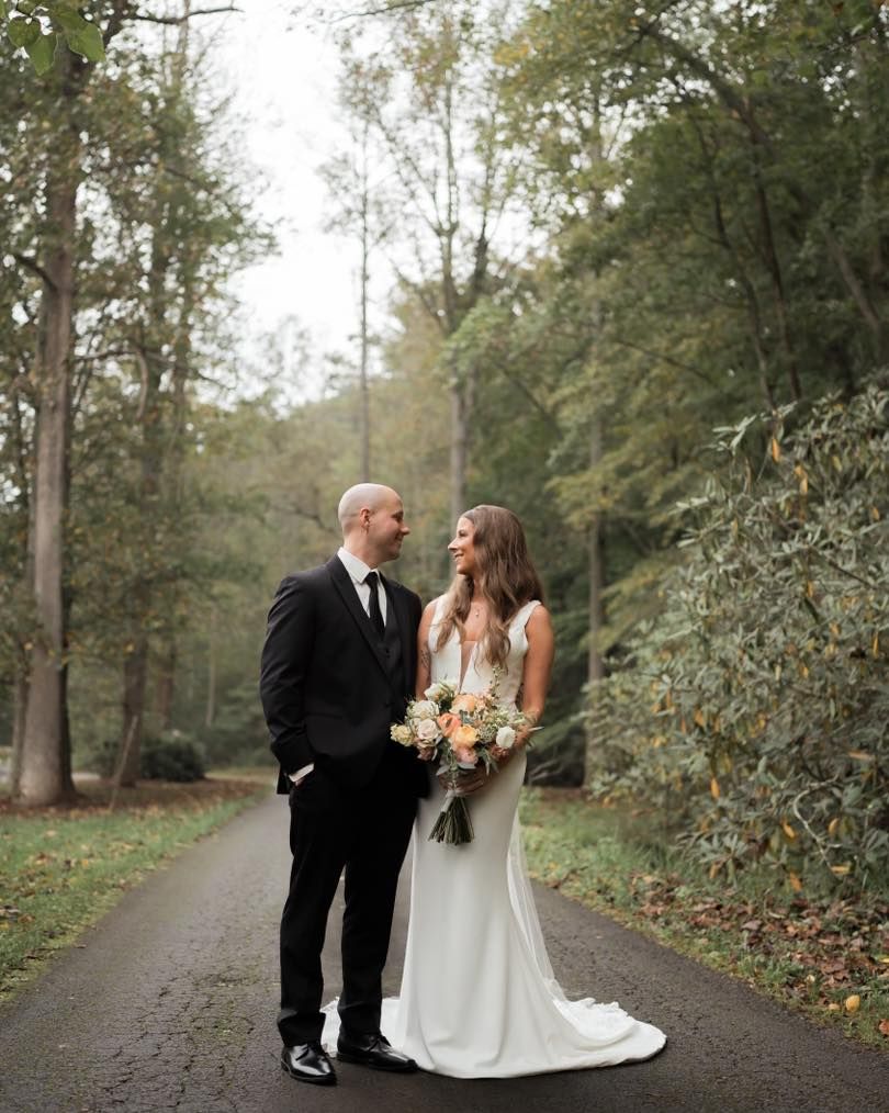 A romantic autumn wedding portrait on a wooded path with warm natural lighting.