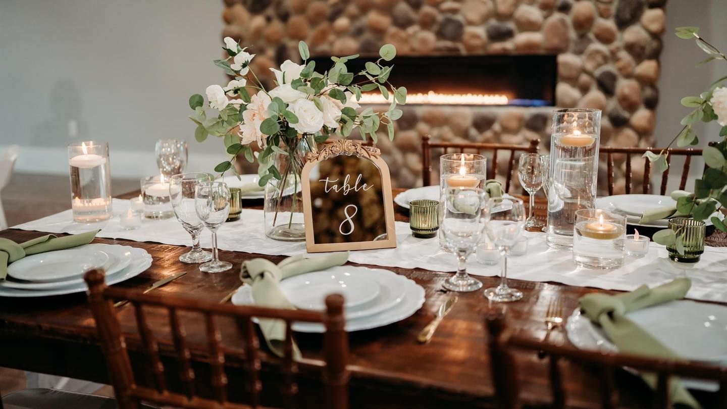 An elegant rustic wedding table setting with greenery, candles and fine dinnerware.