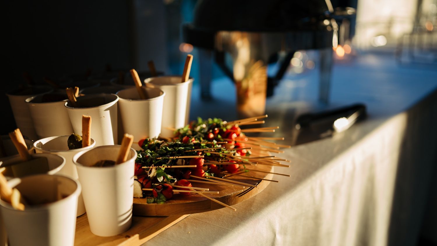 A buffet table with disposable cups and appetizers at a catered event.