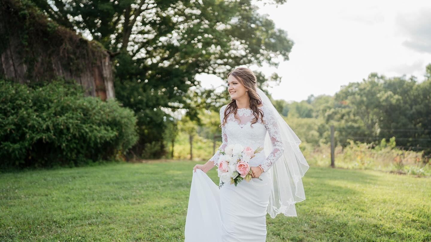Wedding portrait outdoors in a lush garden setting with flowing white dress and veil.