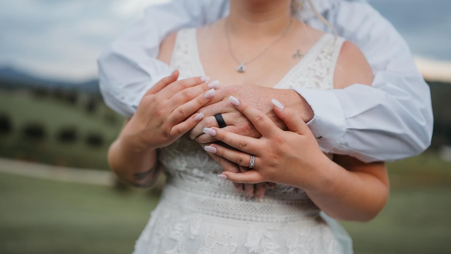 Close-up shot of hands resting on white wedding dress fabric showing delicate details.