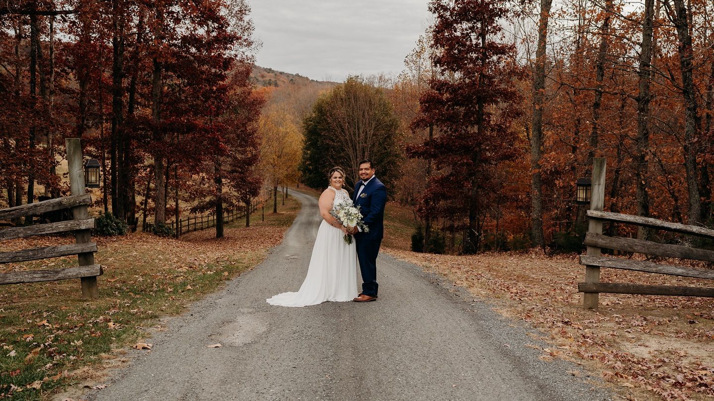 Romantic autumn wedding photo on a country road surrounded by fall foliage.