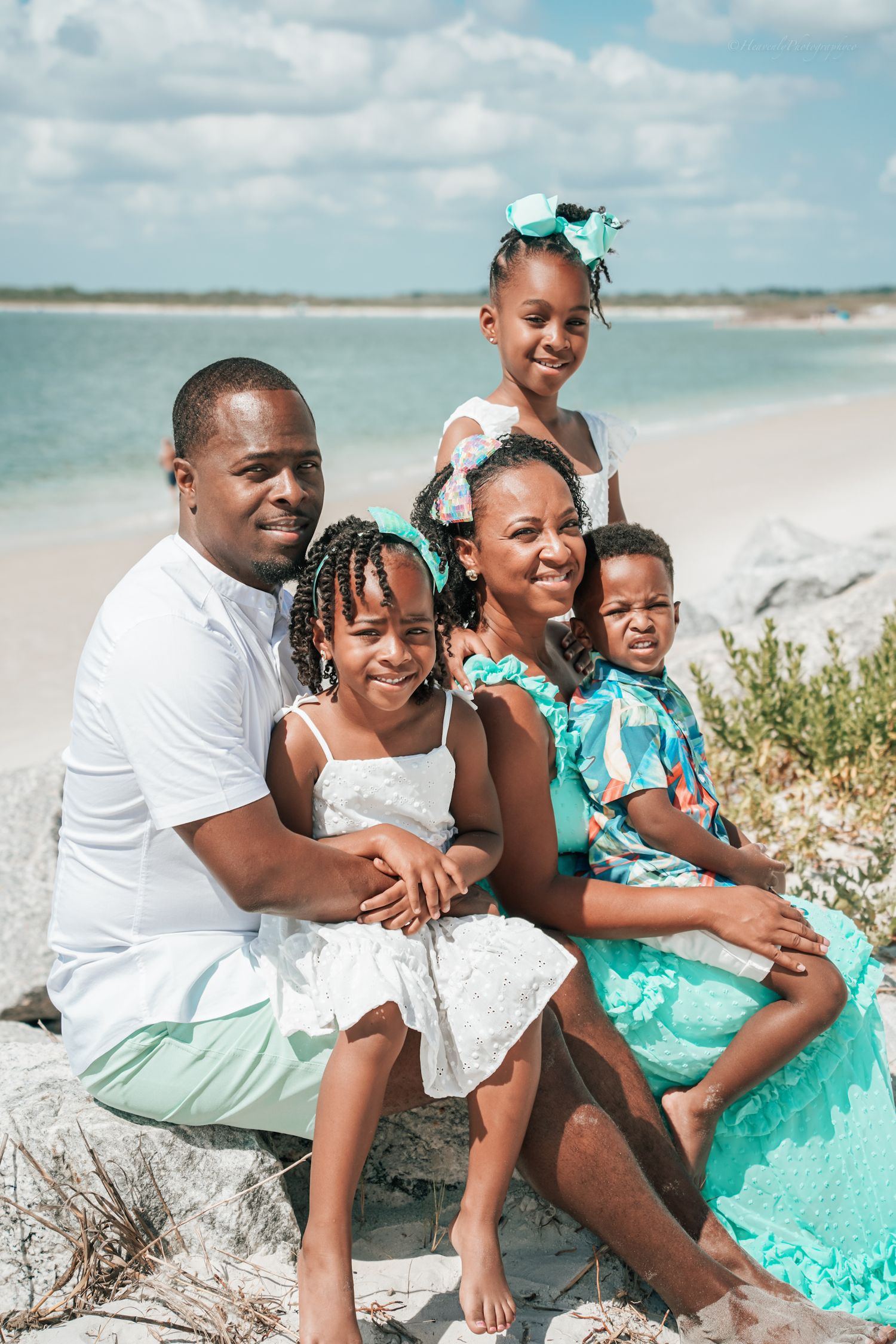 Family dressed in mint green and white enjoys a casual photo session on a sunny beach.