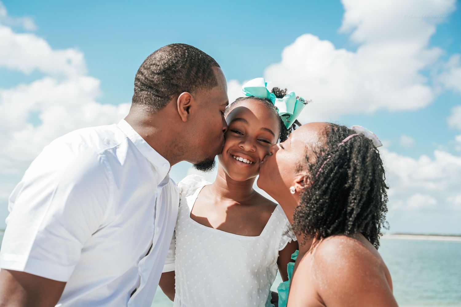 Candid moments of family affection captured during a sunny beach photoshoot.