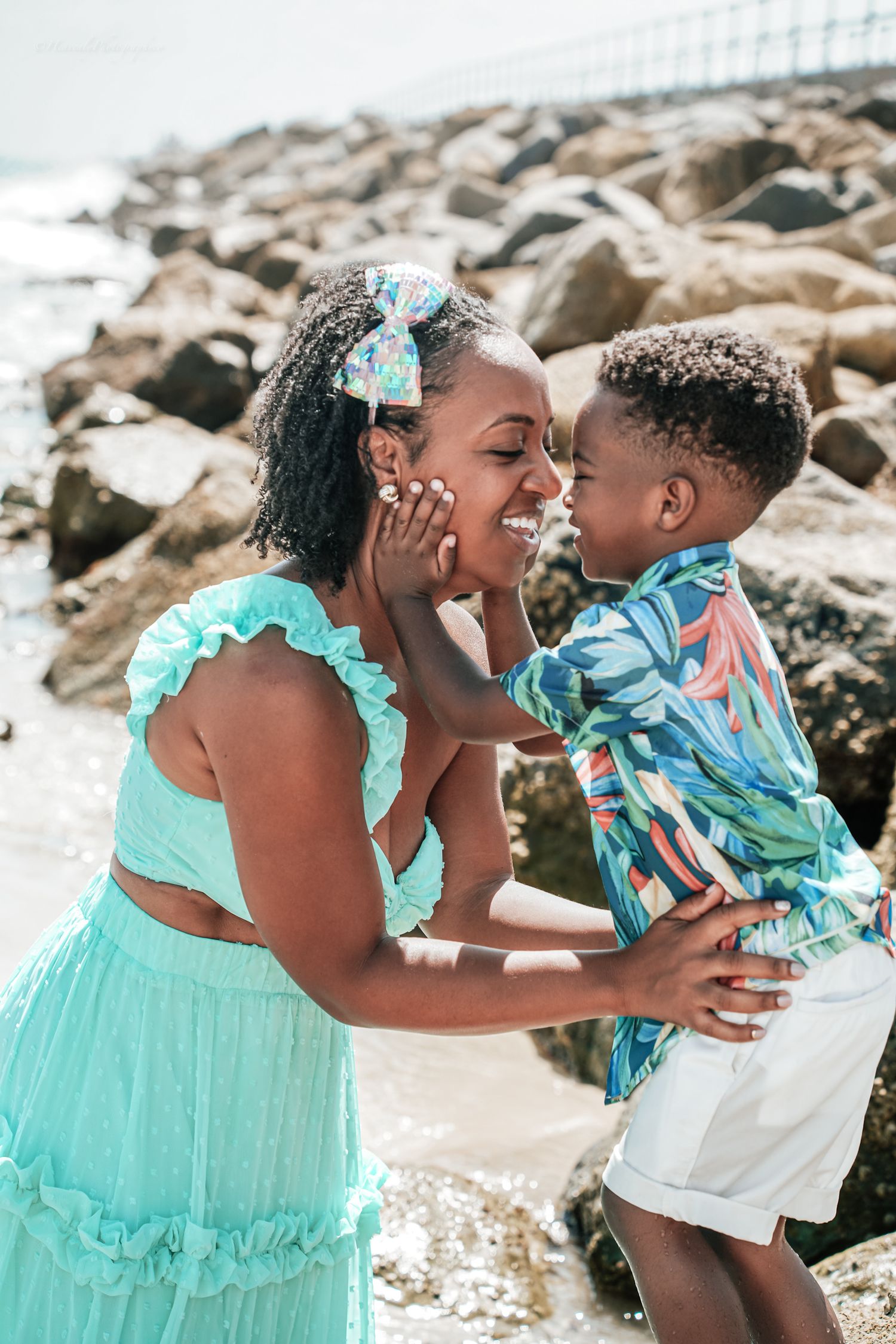 Intimate family moments captured against rocky beach backdrop in matching mint green outfits.