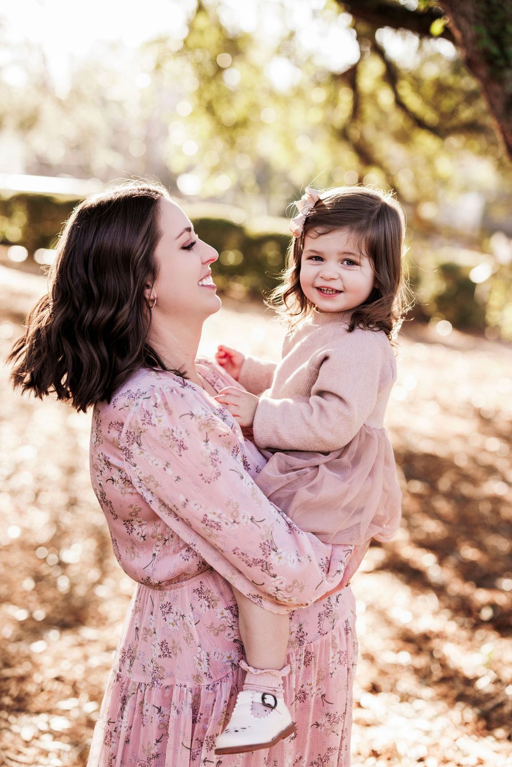 A tender outdoor portrait with matching pink outfits in warm autumn lighting and natural setting.