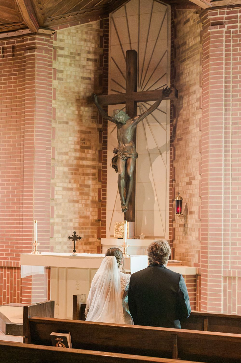 Bride and Groom pray in the adoration chapel after getting married at Parish of Christ the King in Tulsa, Oklahoma.