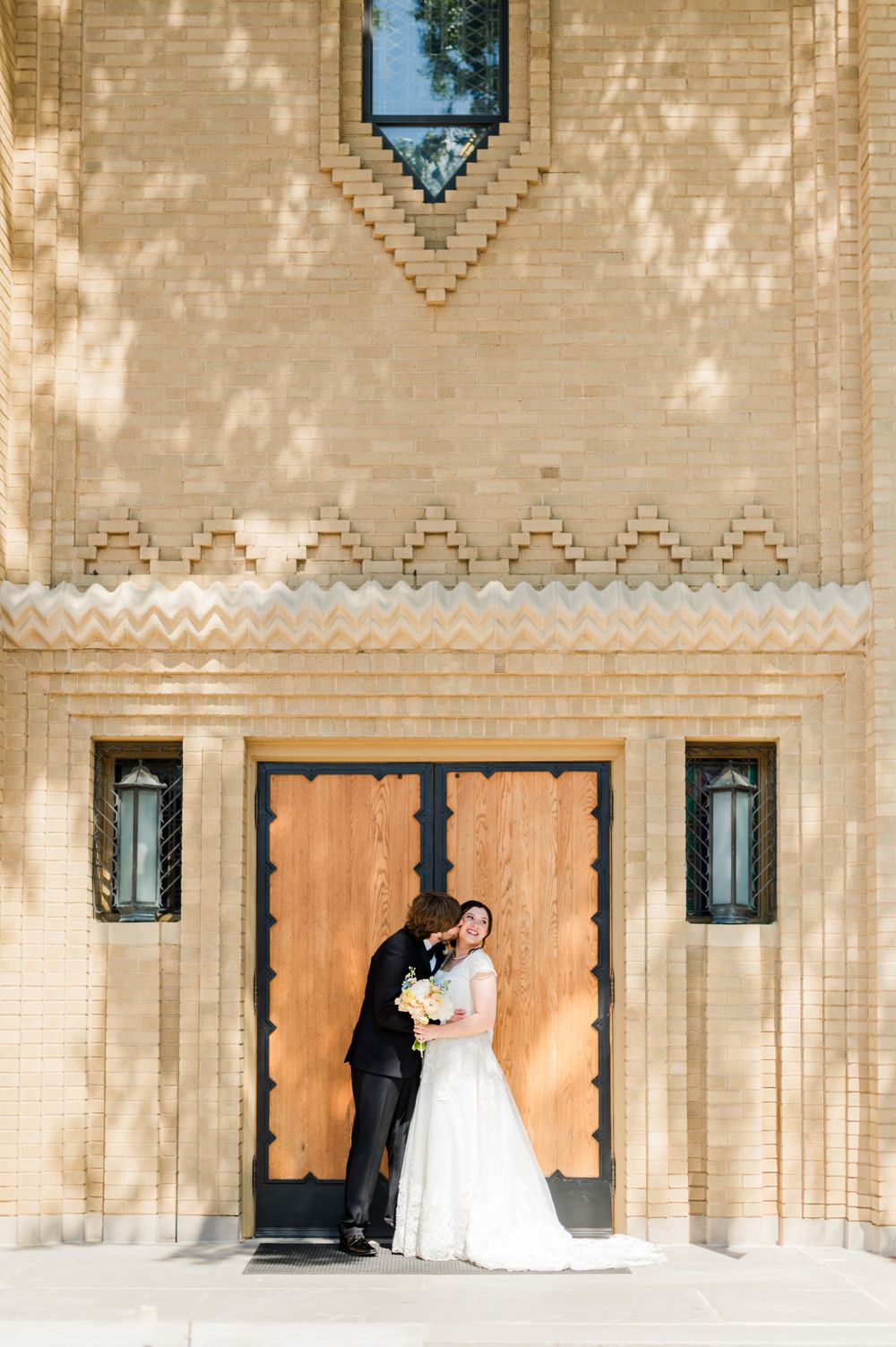 Bride and groom share a kiss on the steps of the Parish of Christ the King in Tulsa, Oklahoma.