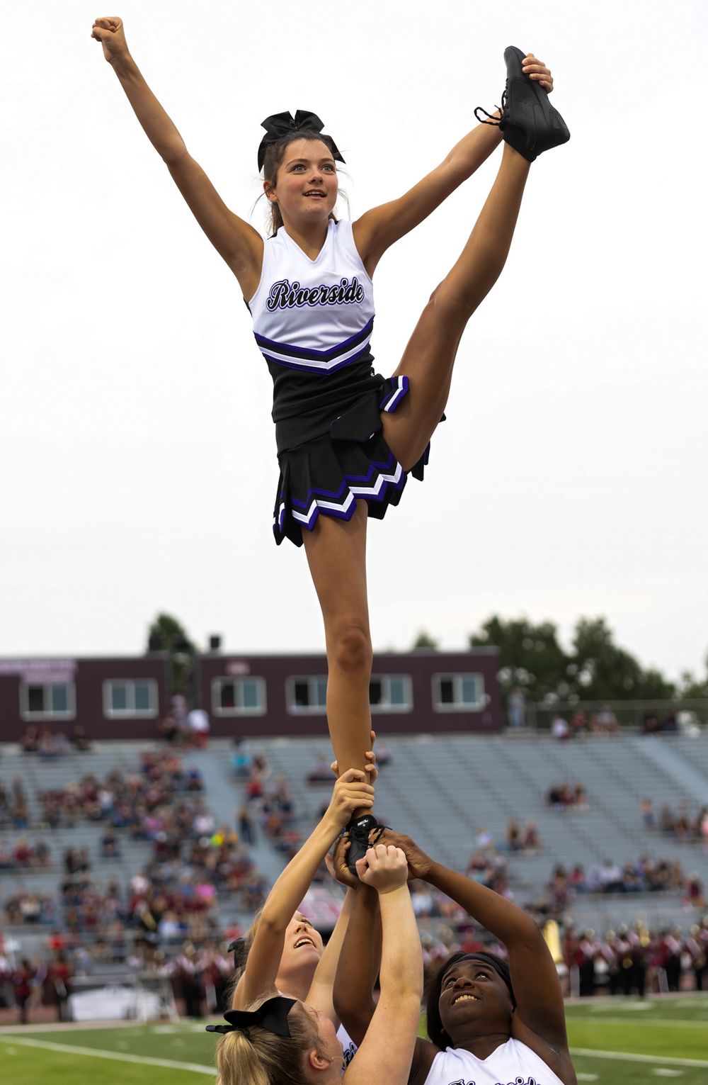 Cheerleader performs dramatic high kick while being lifted by squad members during game performance.
cheer kanawha county riverside