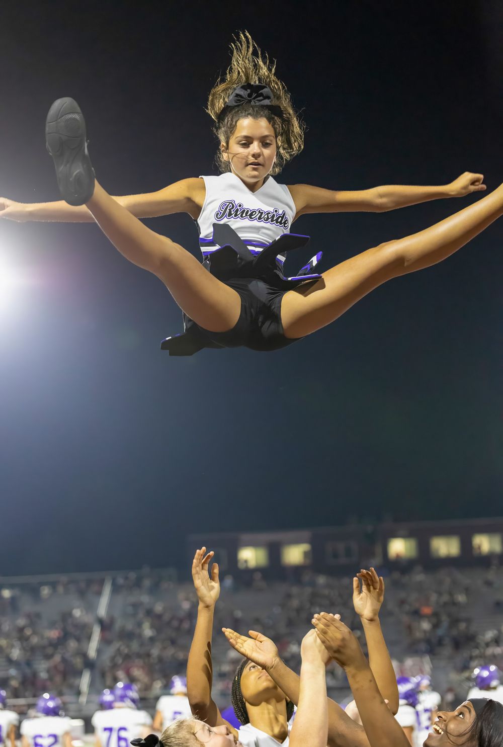 Cheerleader performs impressive toe touch jump during nighttime performance.
cheer kanawha county riverside