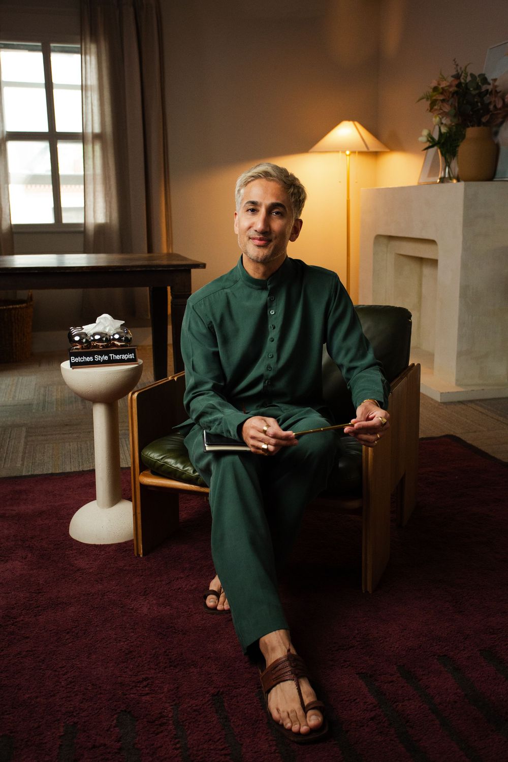 Man in green outfit sitting in leather chair holding a notepad in a warmly lit therapy office setting.
