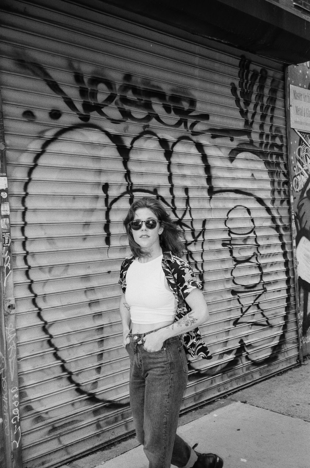Street style photo against graffiti wall wearing sunglasses and casual denim.