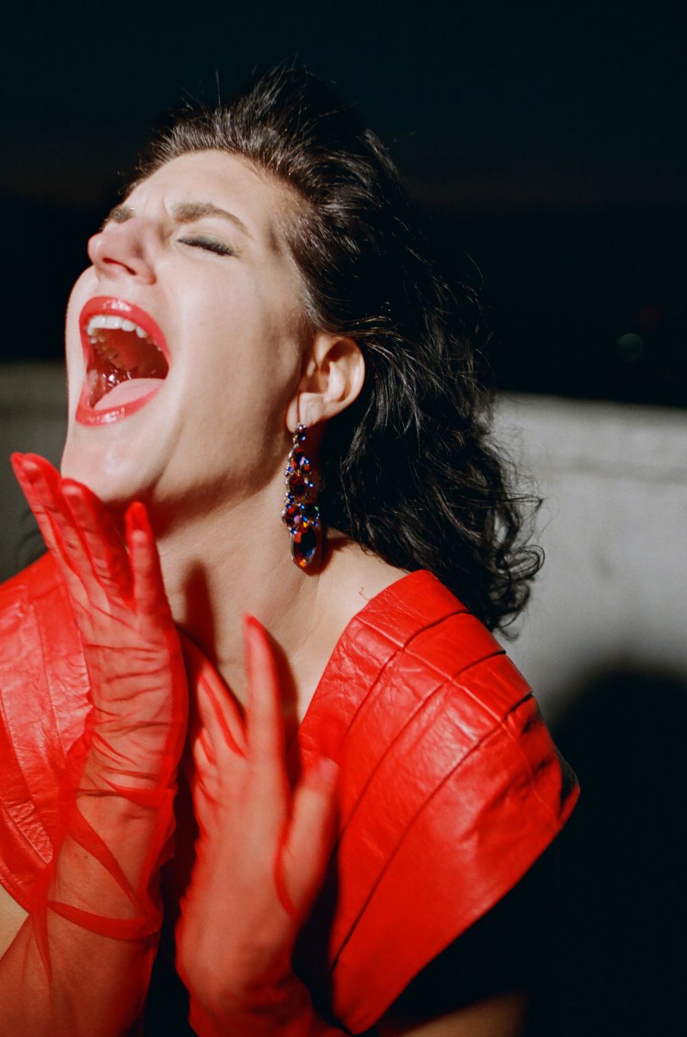 Dramatic portrait in red outfit with expressive pose and bright red lipstick.