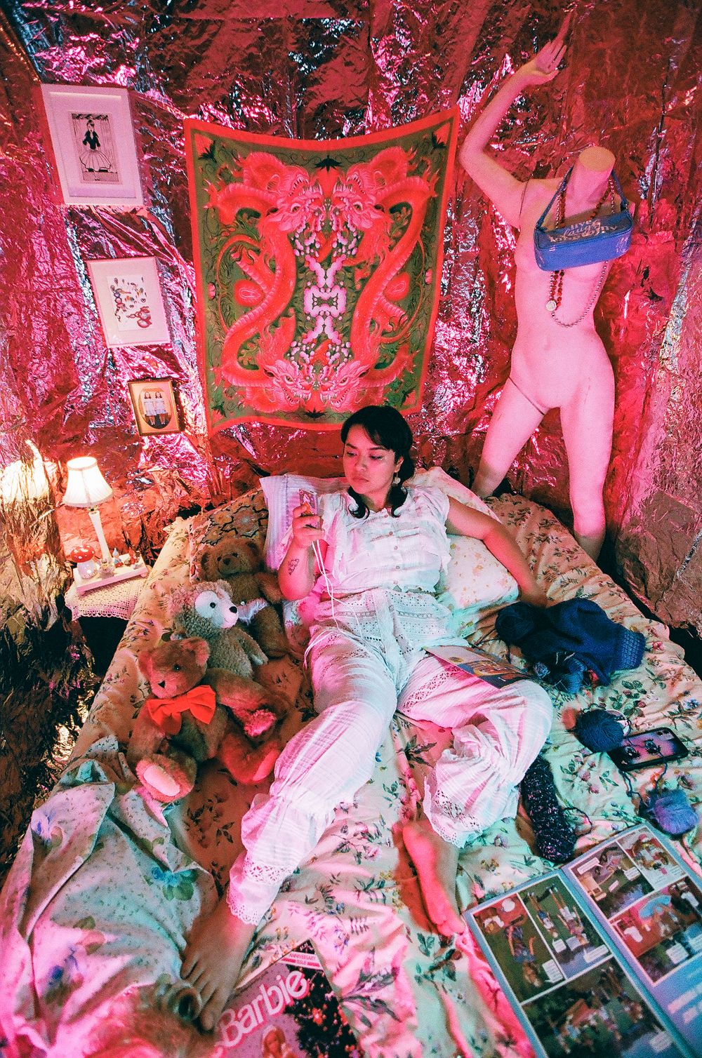 Pink-lit bedroom scene with stuffed animals and magazines scattered on bed.