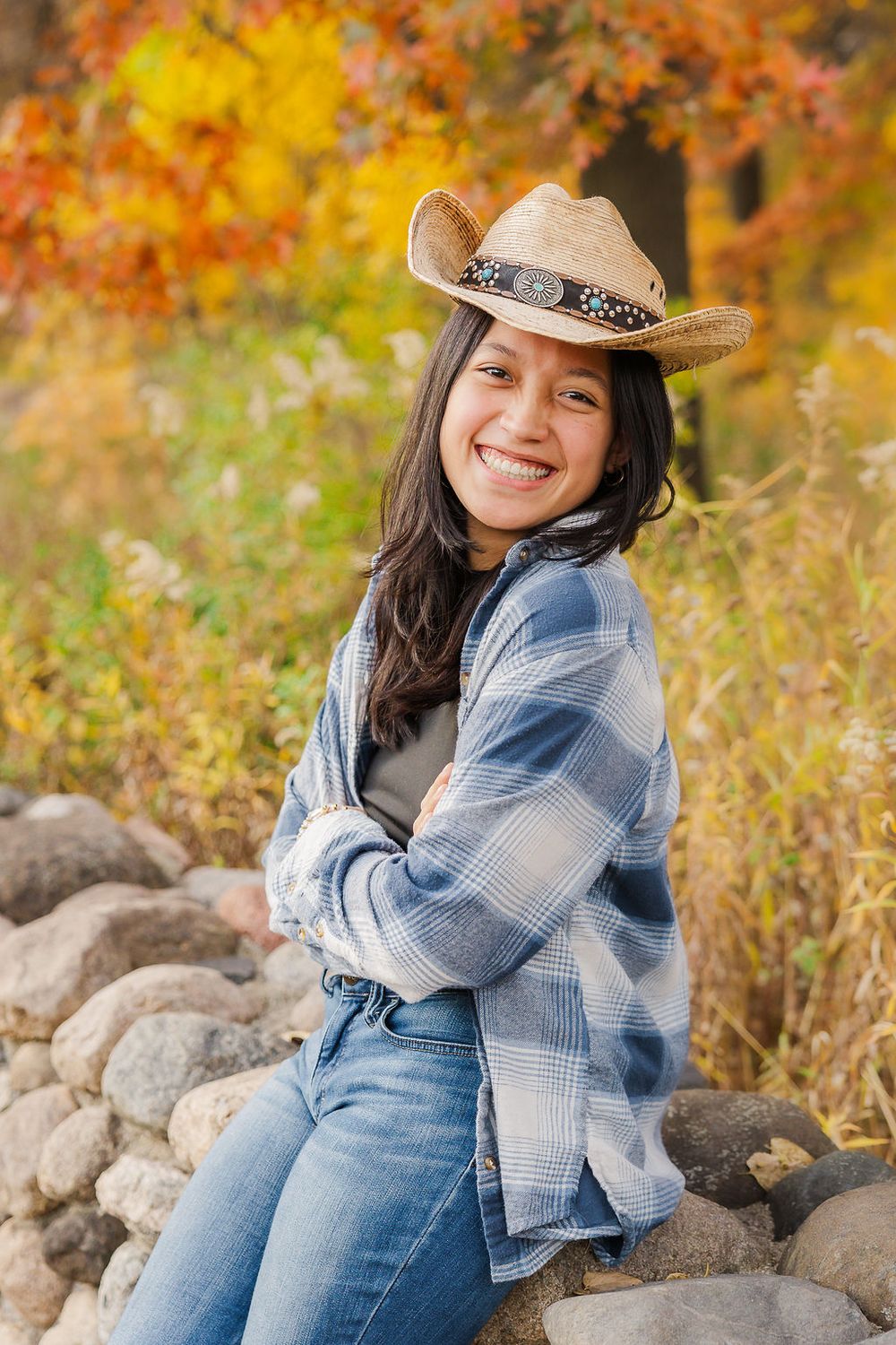 Casual portrait of person wearing cowboy hat and plaid shirt against fall colors.