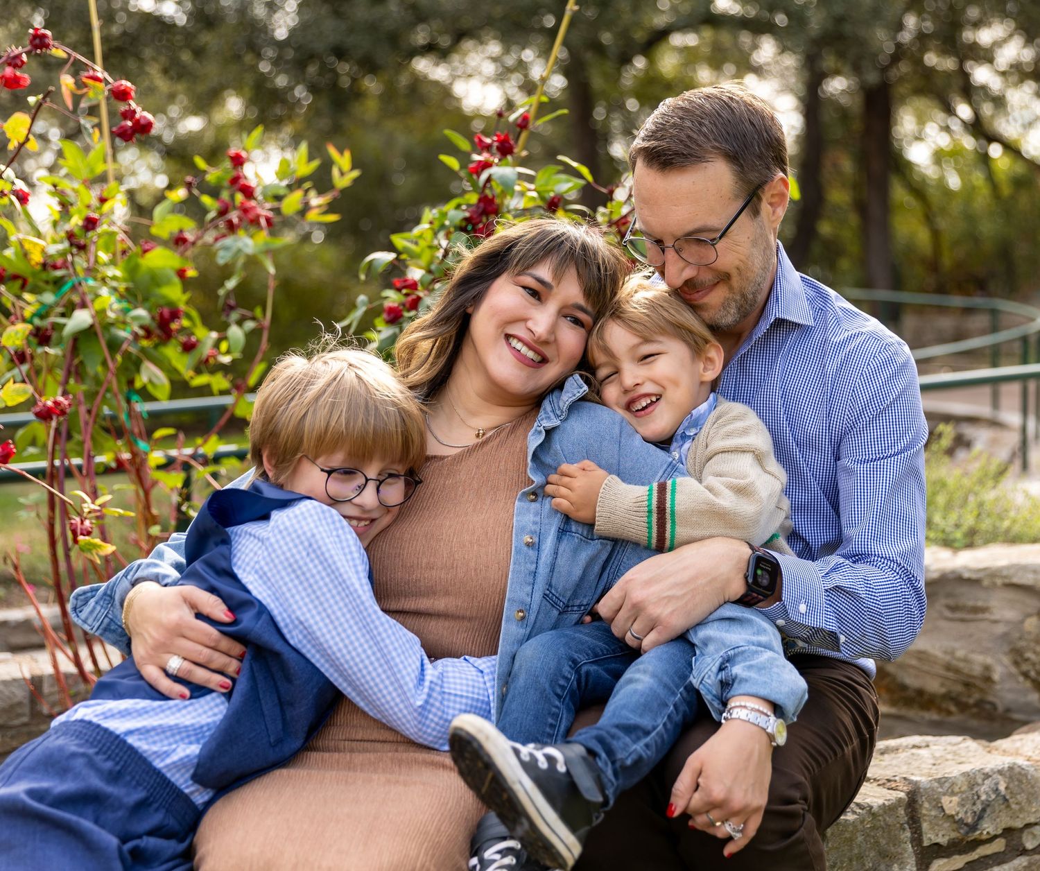 Family sharing joyful moment together outdoors with red berries and foliage in background.