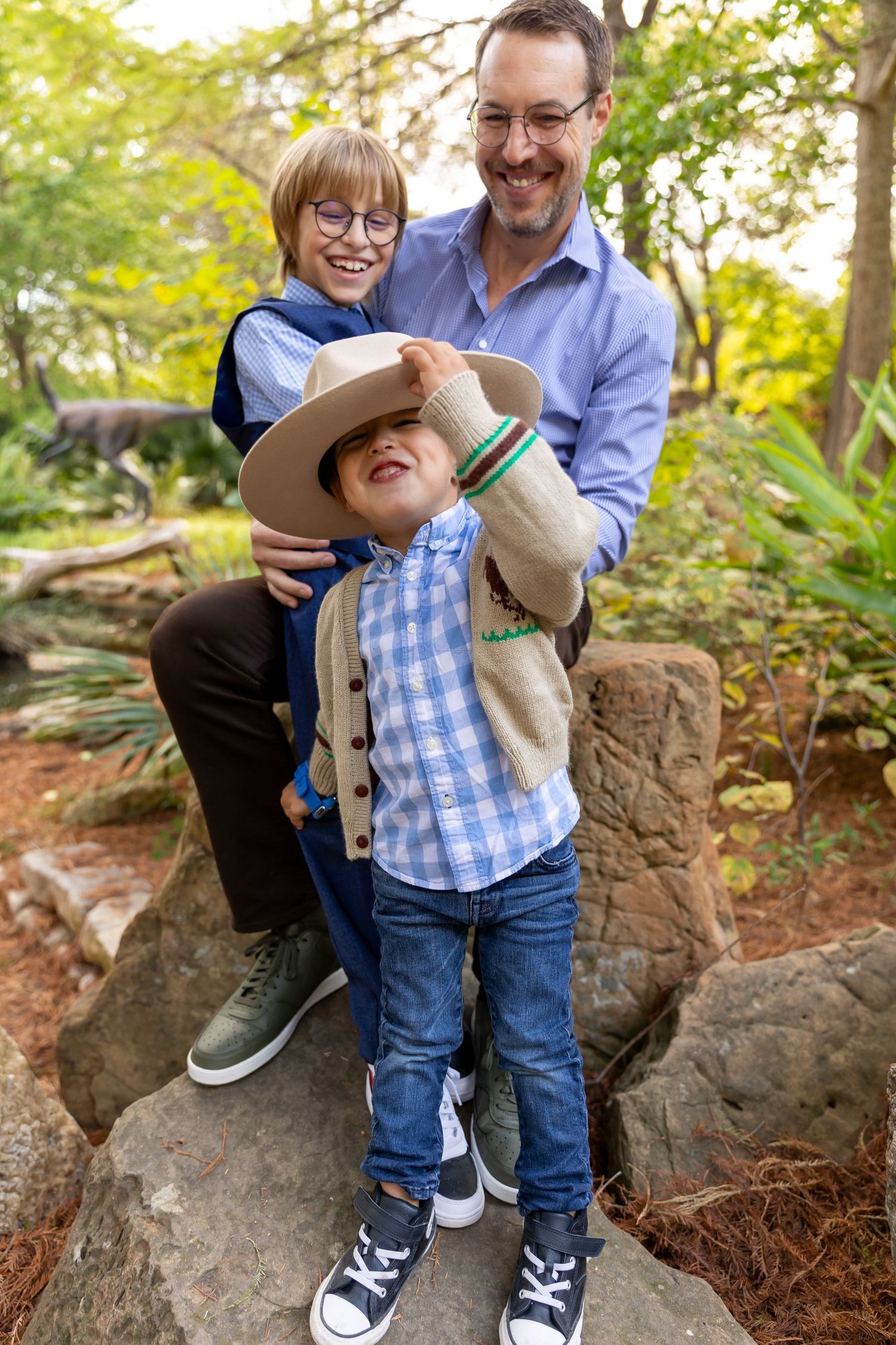 Playful outdoor portrait on rocky terrain with casual clothing and sunlit forest background.