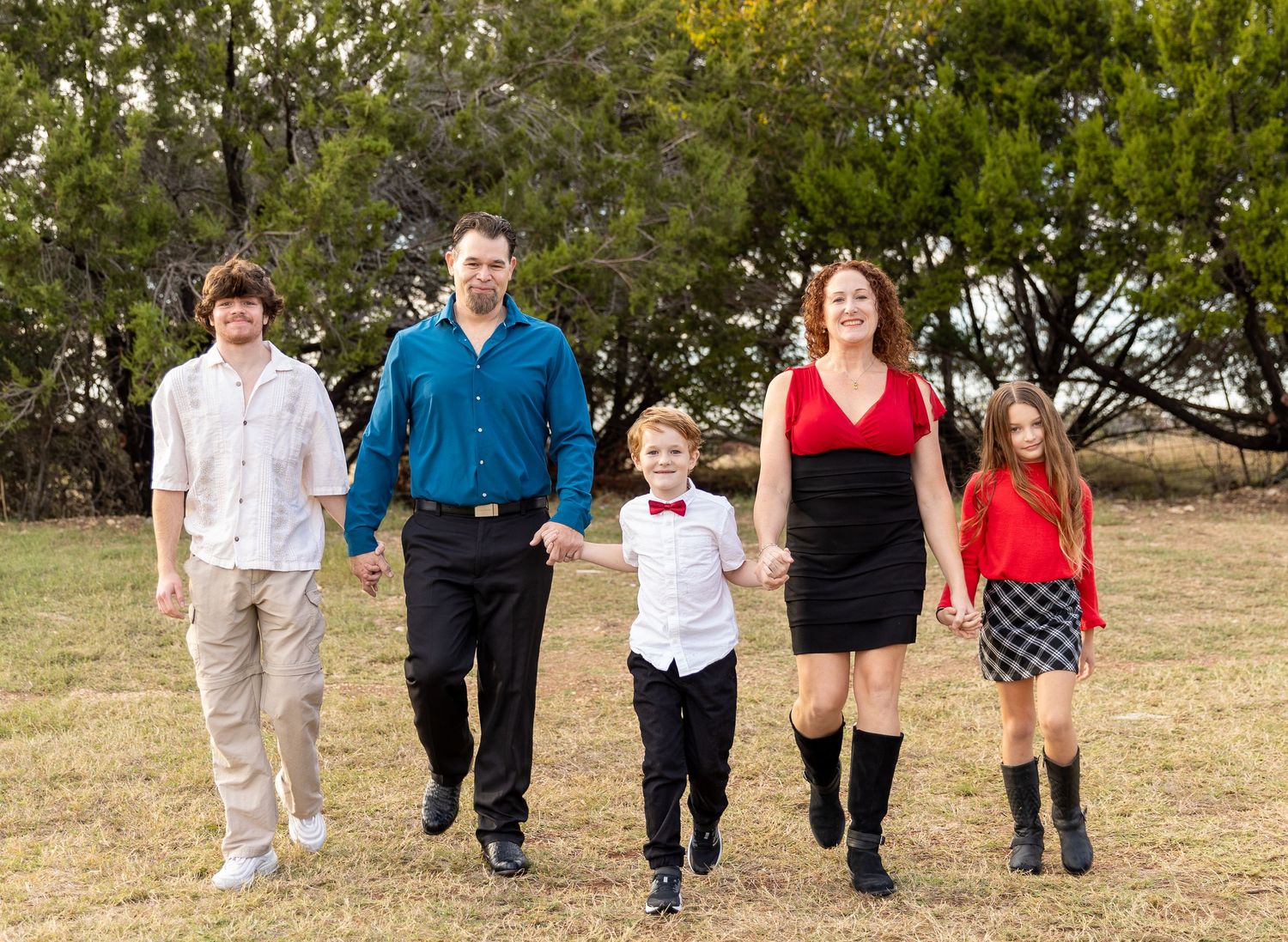 Group walking hand-in-hand across grassy field in casual attire.
