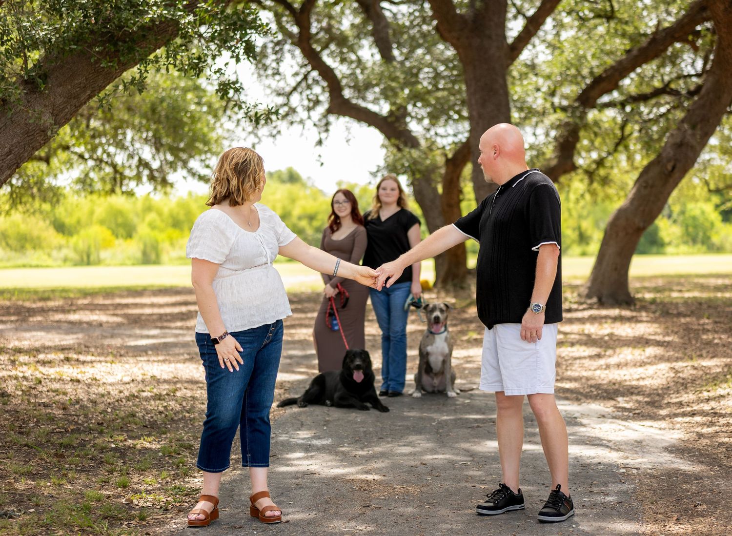 Group gathering under shaded oak trees on sunny afternoon.