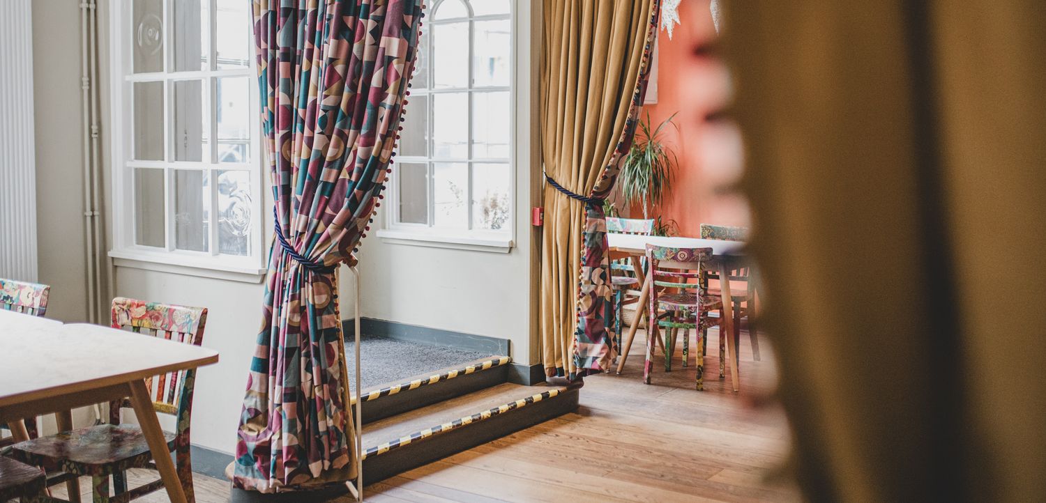 Elegant dining room interior with floral curtains and hardwood floors.