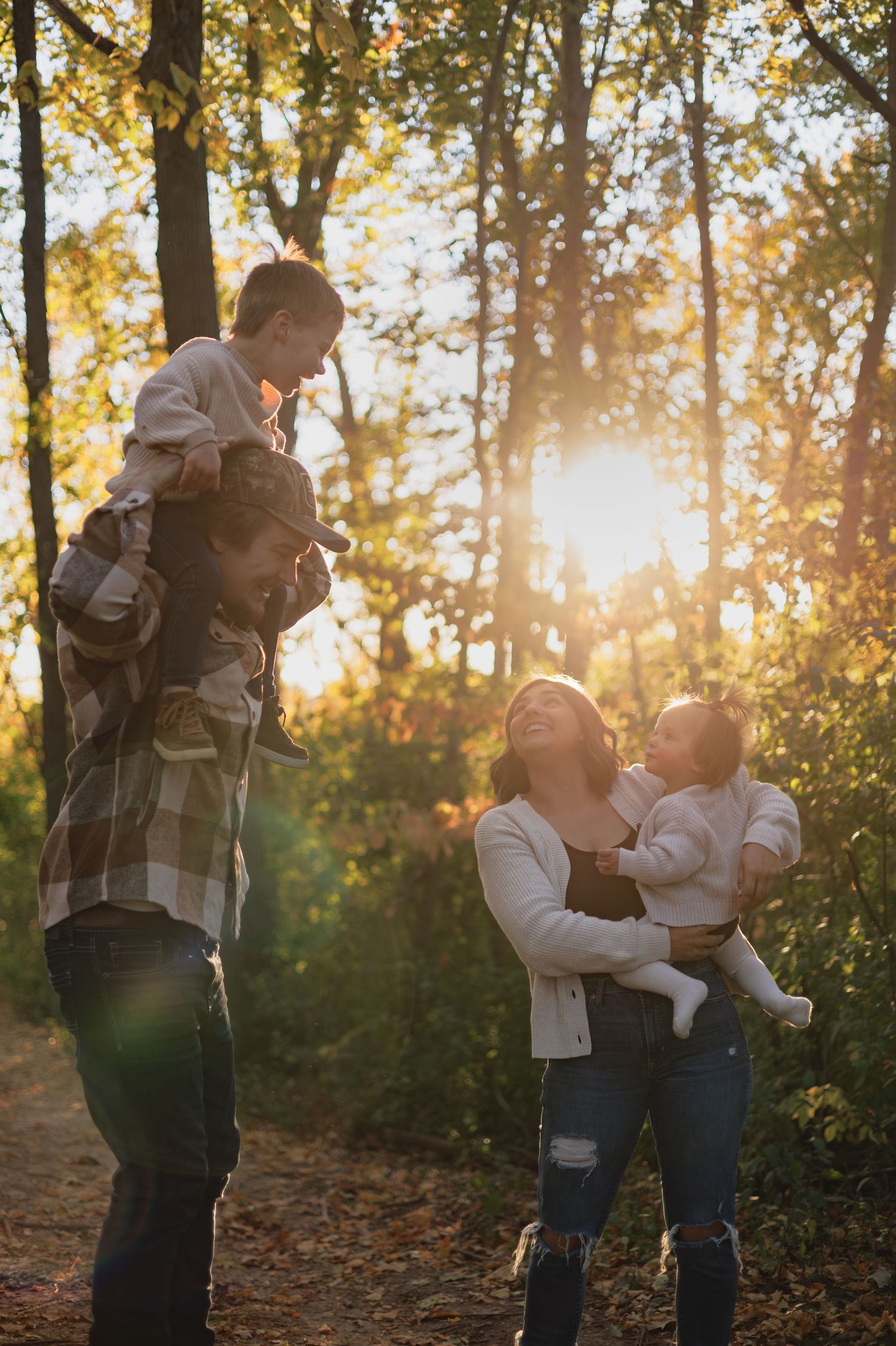 Family sharing a joyful moment together in golden sunset light through autumn trees.