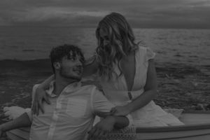 Intimate black and white photo of a couple sharing a tender moment by the sea.