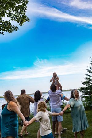 Group of people holding hands in circle outdoors against blue sky.