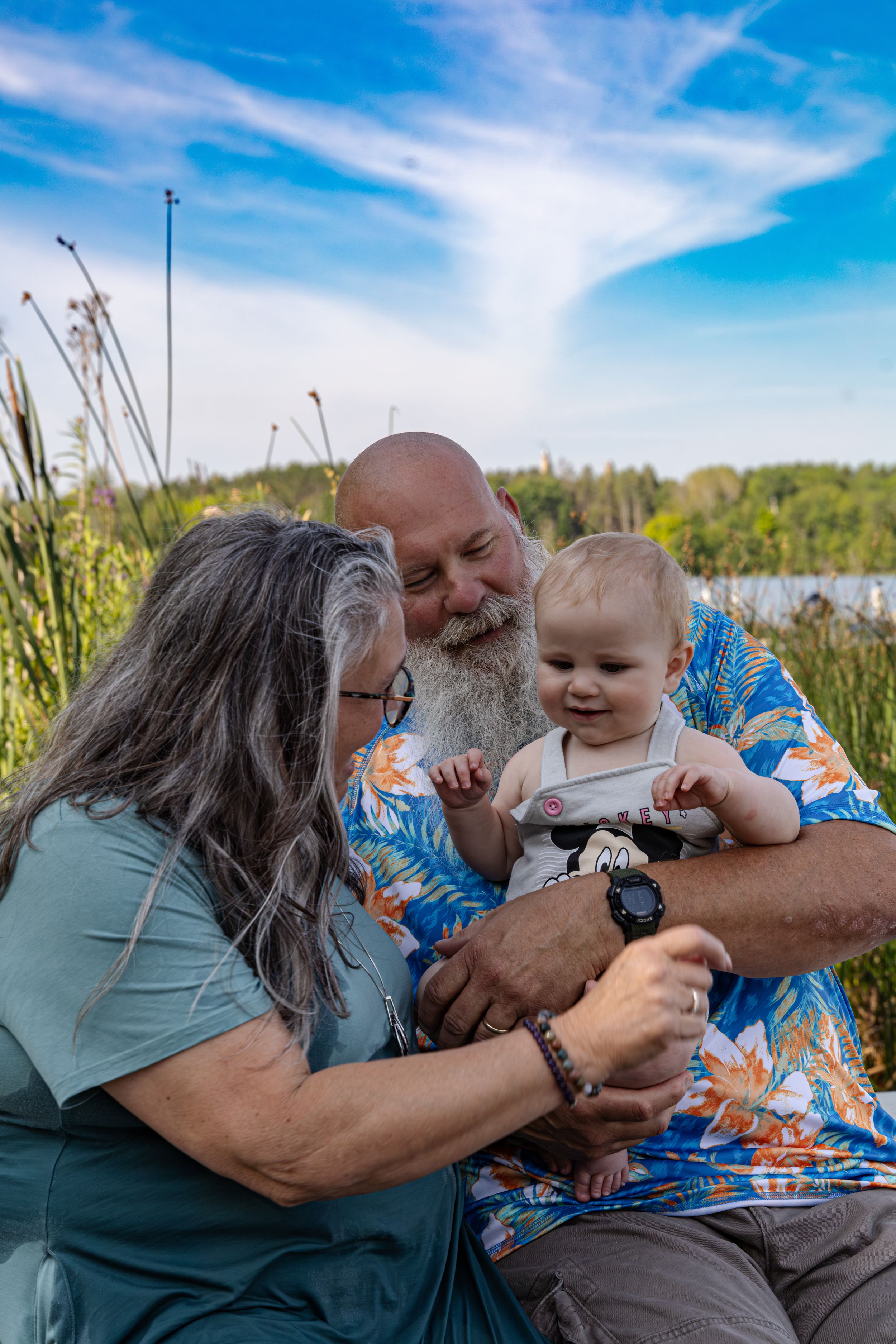 Grandparents sharing tender moments outdoors against blue sky and natural landscape.