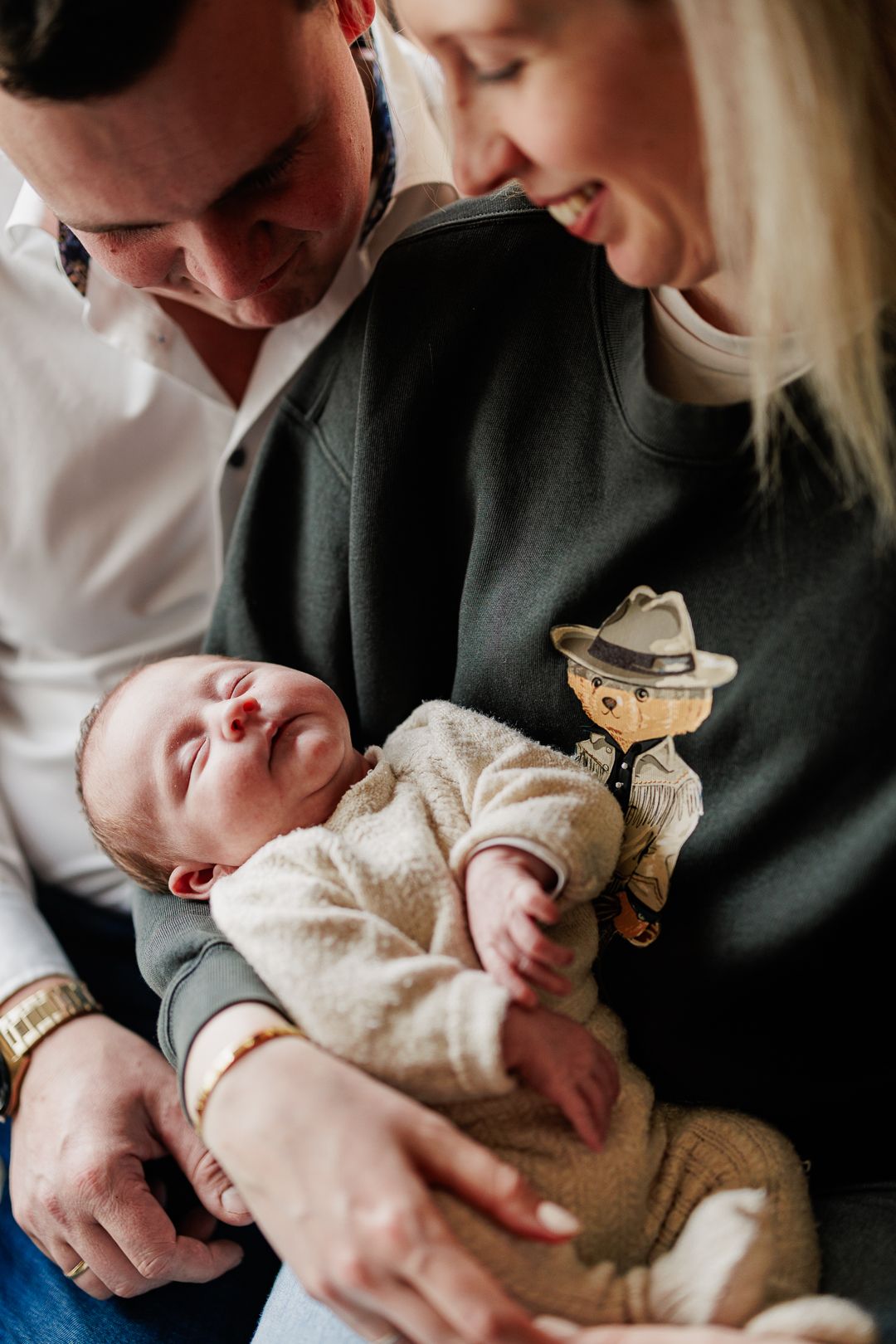 A tender moment with a baby being held in a cozy white onesie.