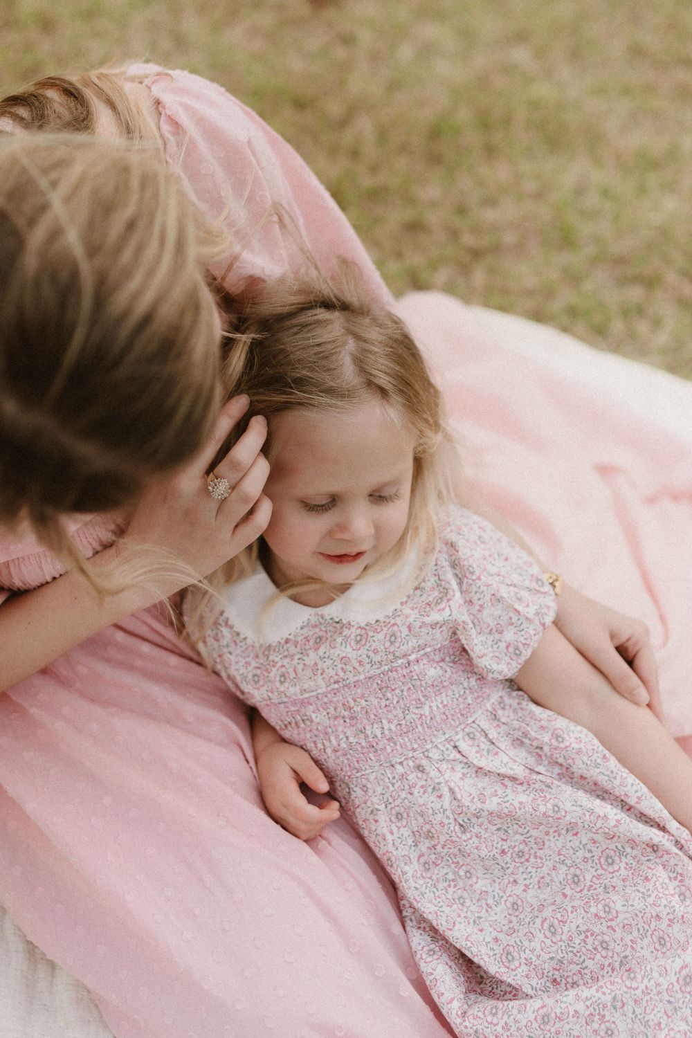 Gentle embrace shared on a pink blanket during an outdoor photoshoot.