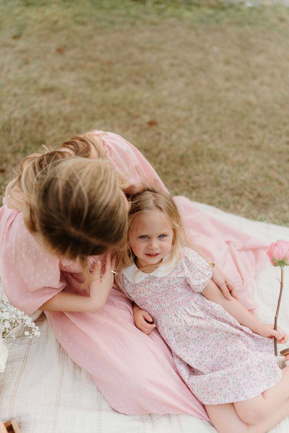 Joyful outdoor moments captured on a blanket with pink spring attire.