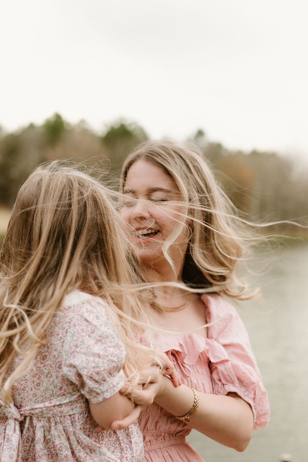 Candid moments of laughter and play captured in soft pink tones by the waterfront.
