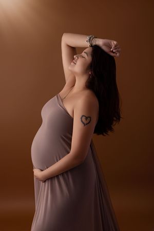 Artistic maternity photo series showing a pregnant woman in a gray dress against a brown background.