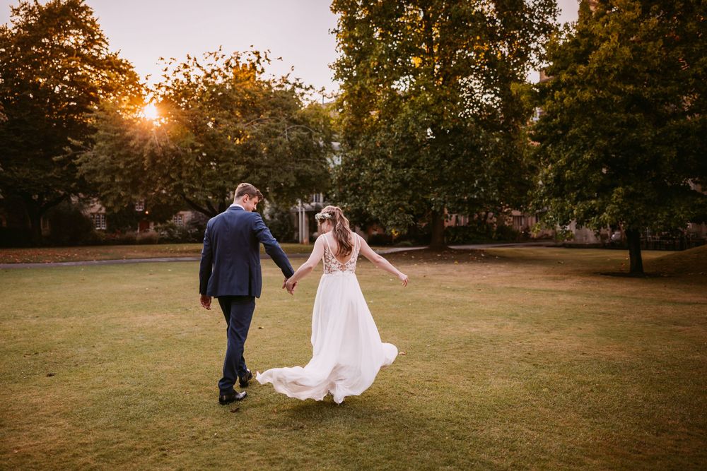 Bride and Groom dance playfully on a lawn during their fall wedding photoshoot at Balliol College, Oxford