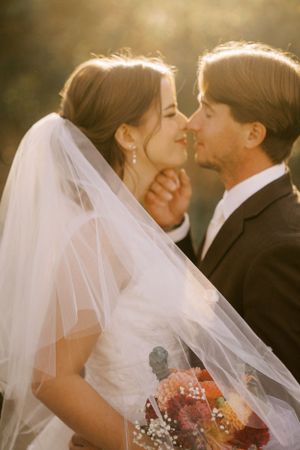A romantic sunset wedding portrait with a delicate veil and bouquet.