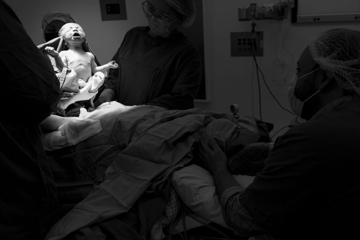 Medical team performing surgery in dark operating room with focused lighting.