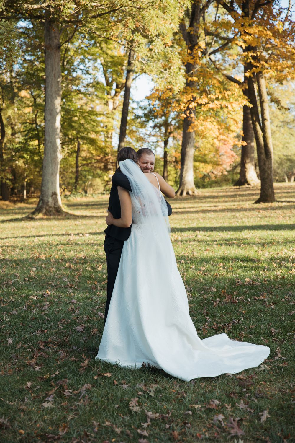 Newlyweds share a romantic moment in an autumn park with golden leaves.