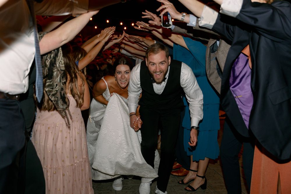 Wedding reception dance floor filled with celebrating guests under dim lighting.
