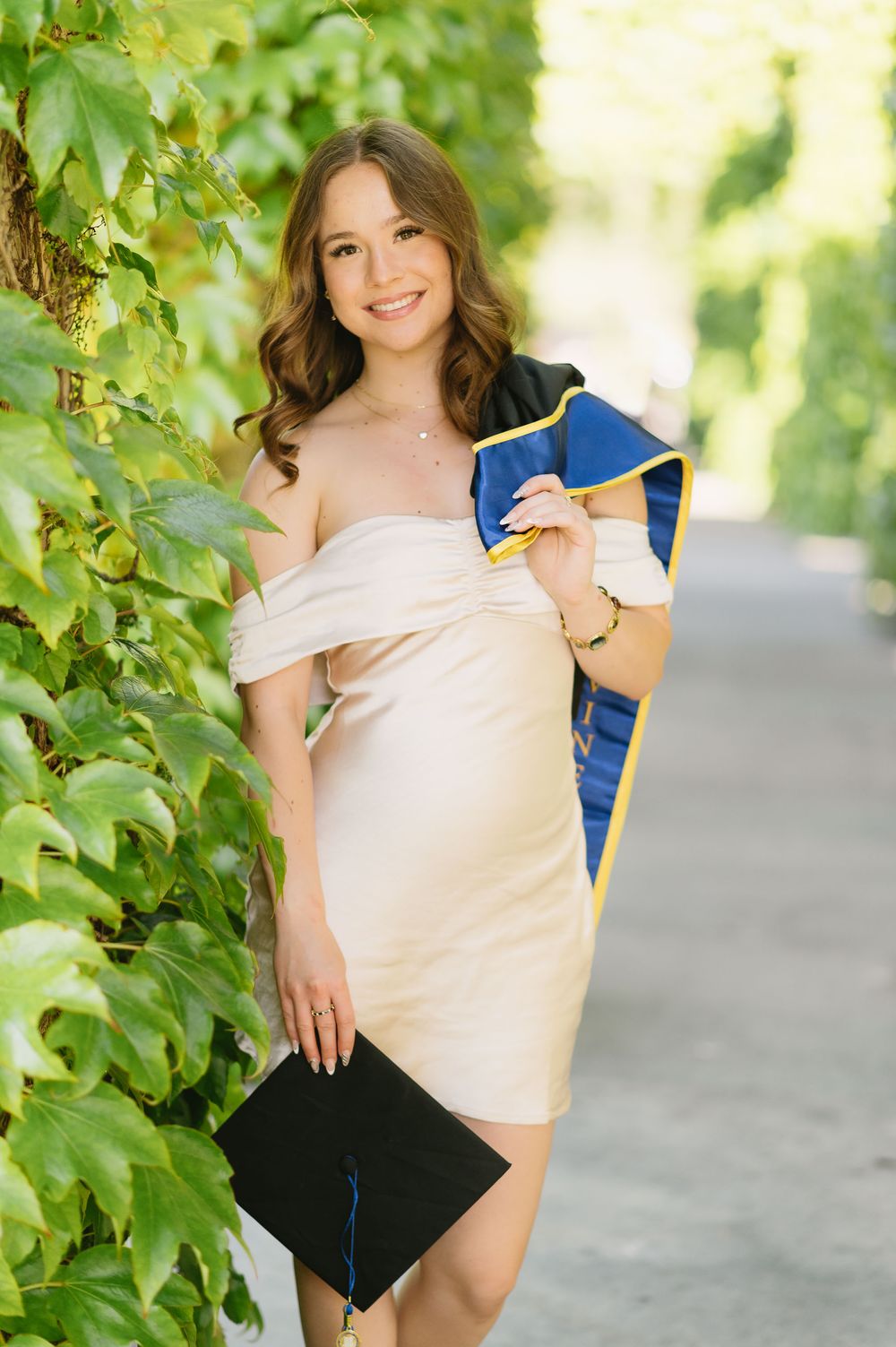UCI graduate in cap and gown posing on the University of California, Irvine campus