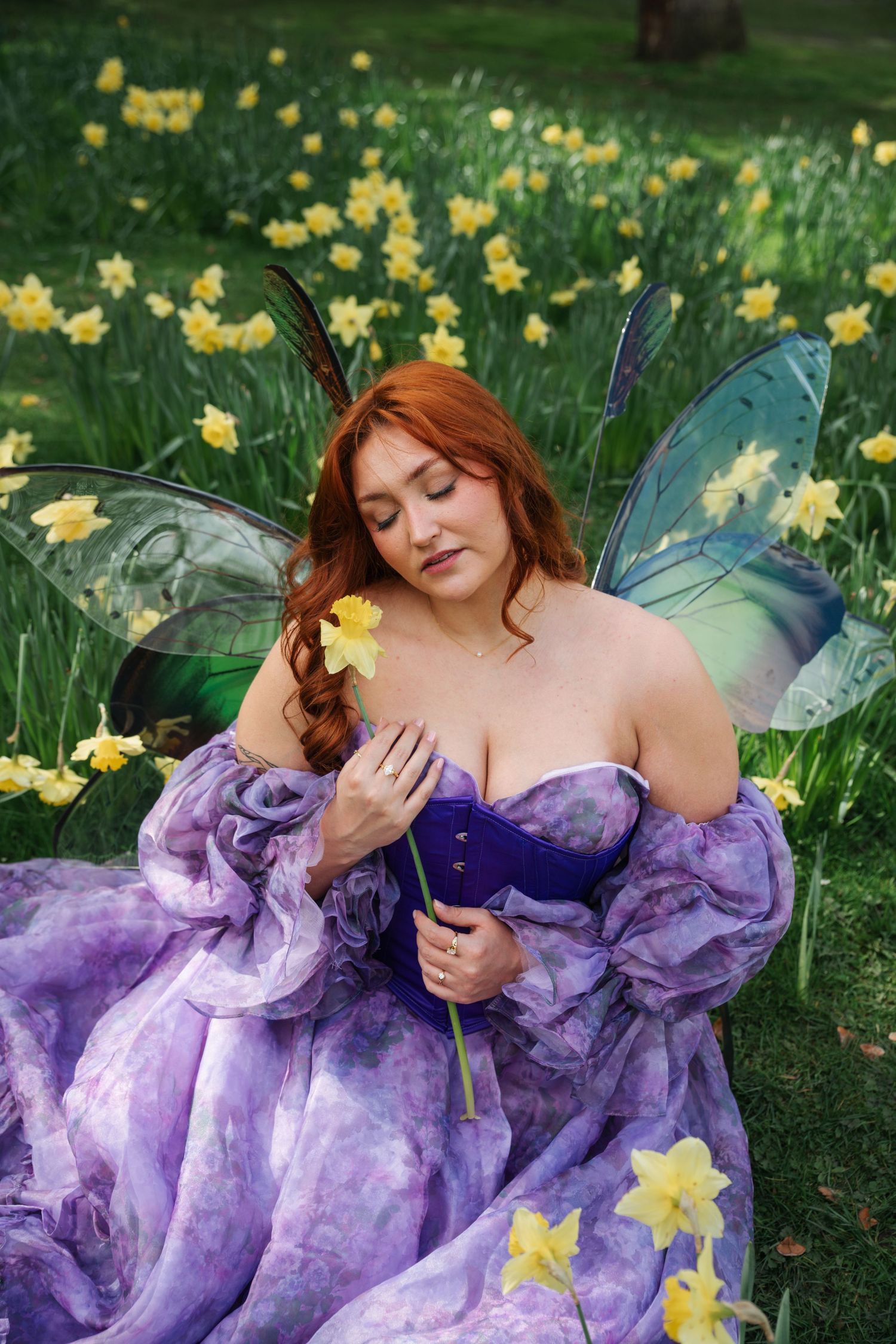 Fantasy-themed portrait of a figure lying in grass with blue flowers and a sword.