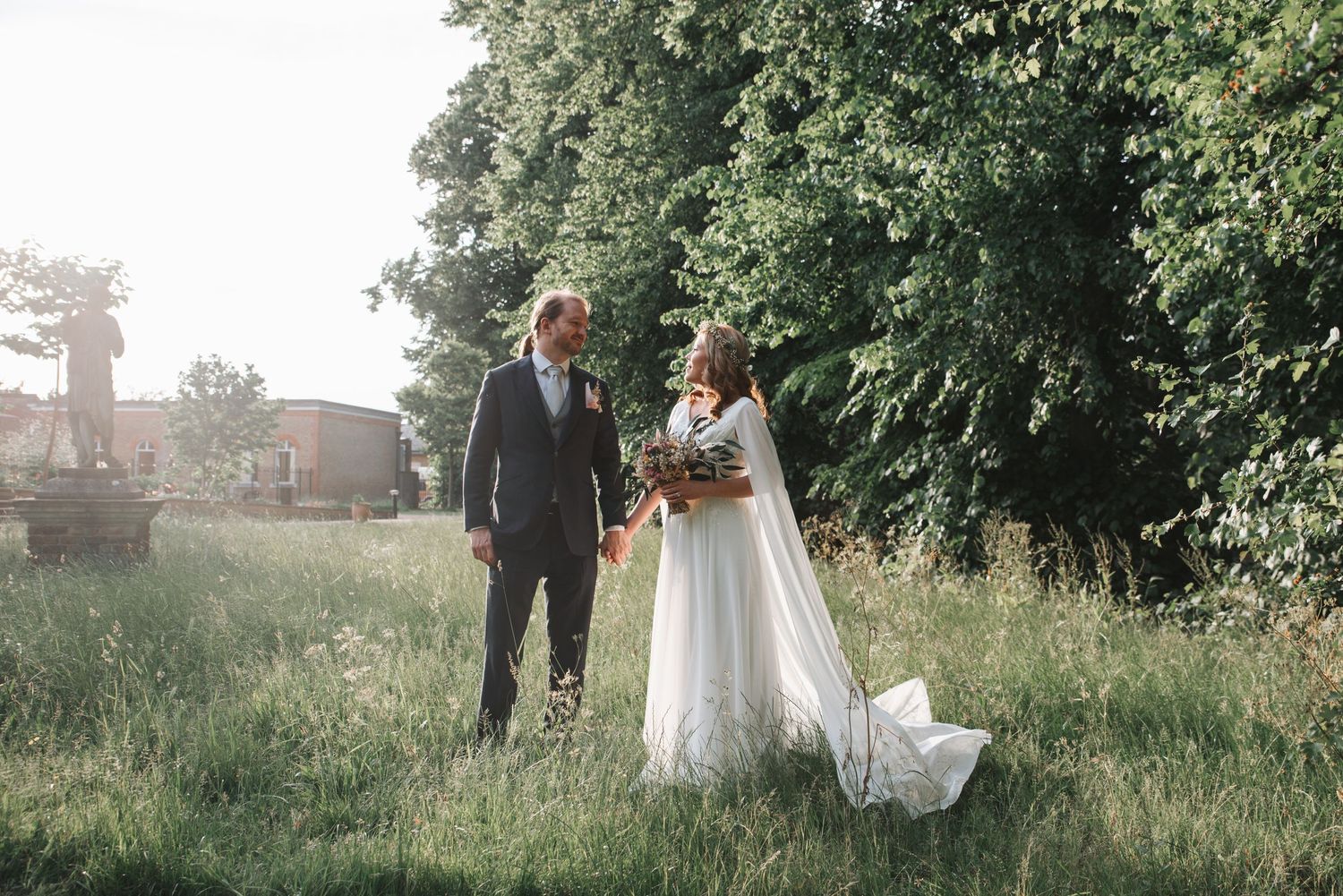 A couple walks through a lush green garden setting during an outdoor photo session.