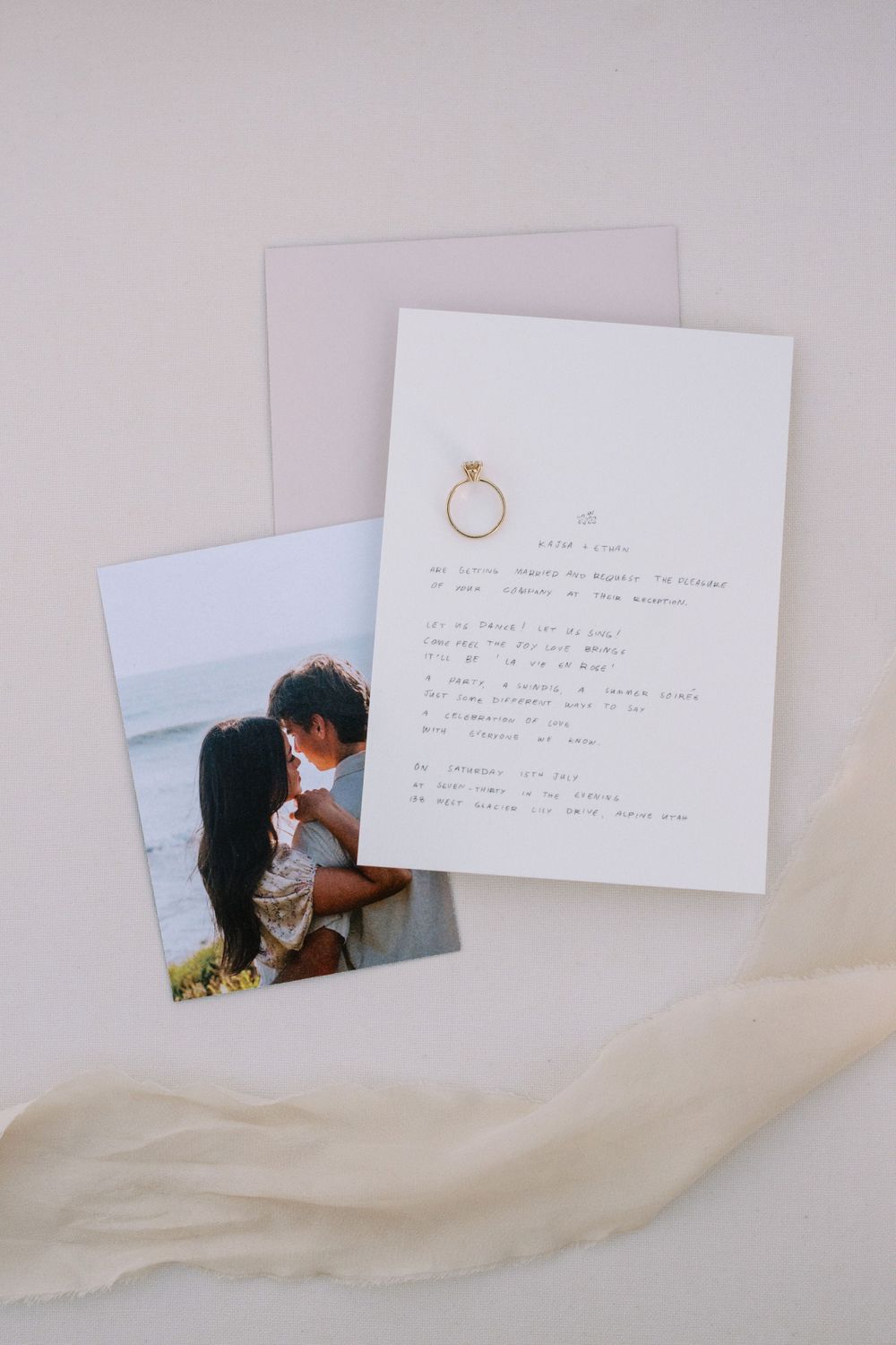 A romantic photograph and handwritten note with a delicate gold ring illustration displayed on a soft fabric background.