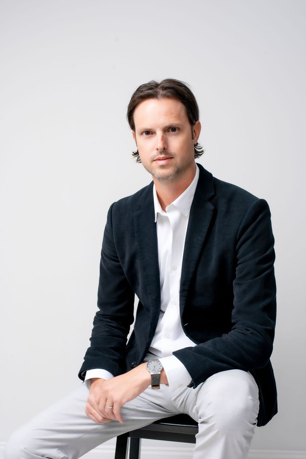 Professional headshot of a male lawyer in studio, wearing a suit and tie, looking confident and approachable.