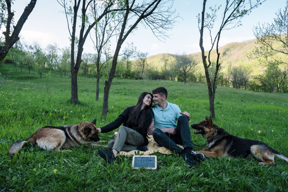 A couple and their dog enjoy a relaxing moment on a grassy hillside during spring.