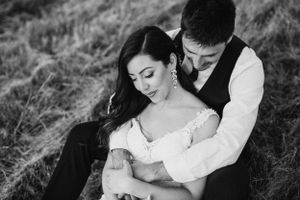Black and white portrait of tender embrace during rustic outdoor wedding photoshoot.