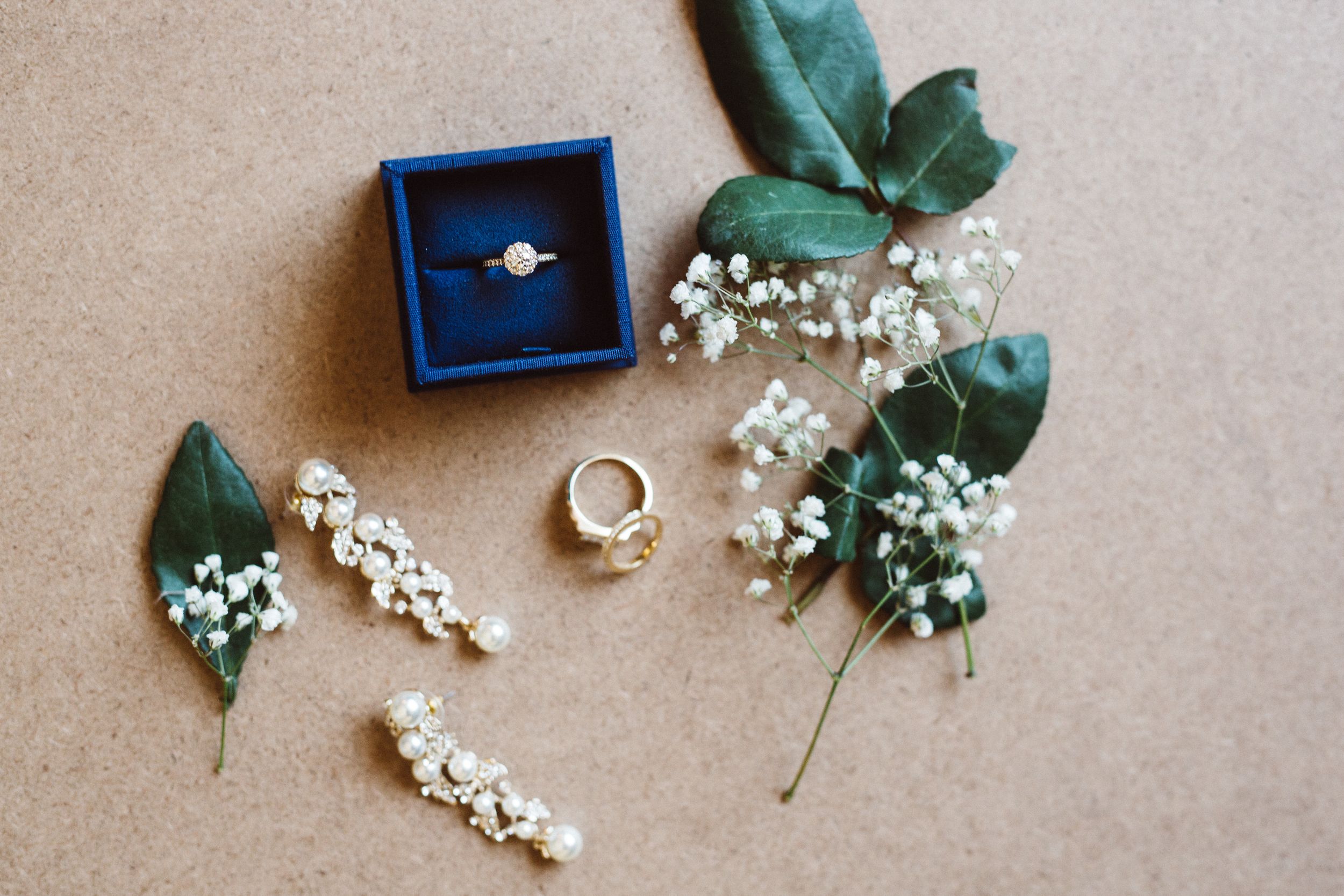 Wedding rings and delicate baby's breath flowers arranged on neutral background.