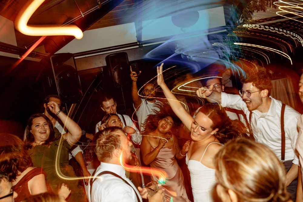 Lively wedding reception dance floor with light trails and celebrating guests.