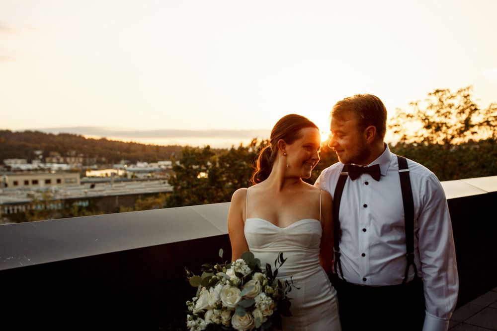 Intimate sunset portrait of newlyweds against cityscape backdrop.