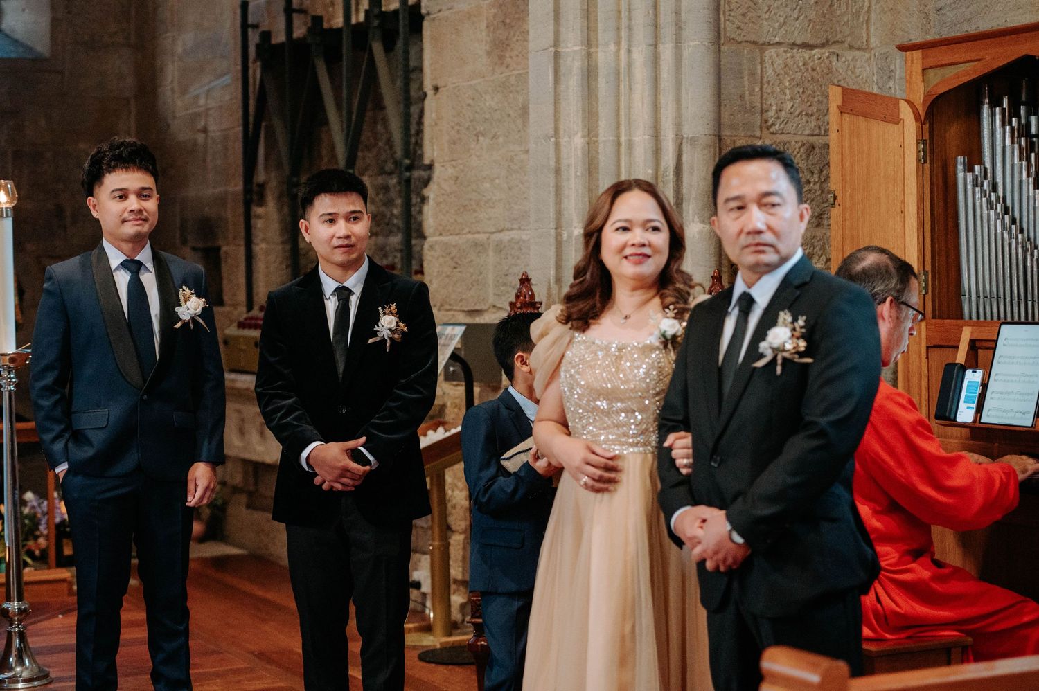 Wedding party members lined up inside church with stained glass windows.
