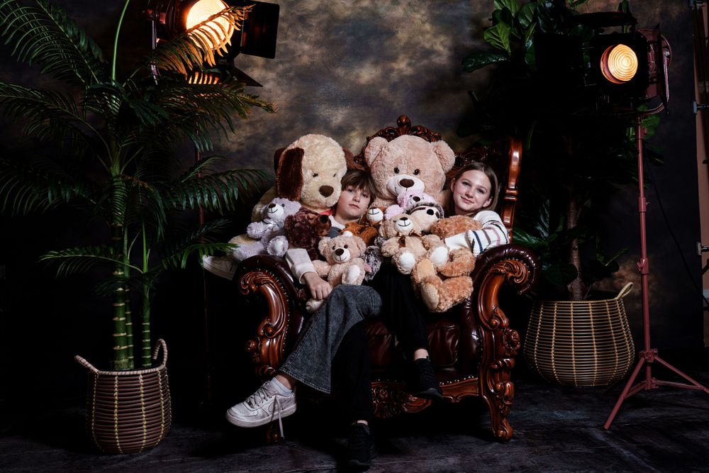 A charming scene with teddy bears and stuffed animals arranged on a vintage brown leather armchair with studio lighting.
